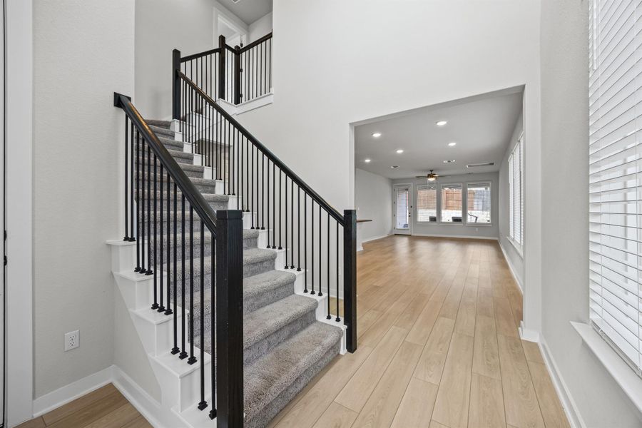 Stairs featuring wood finished floors, recessed lighting, a towering ceiling, and a ceiling fan