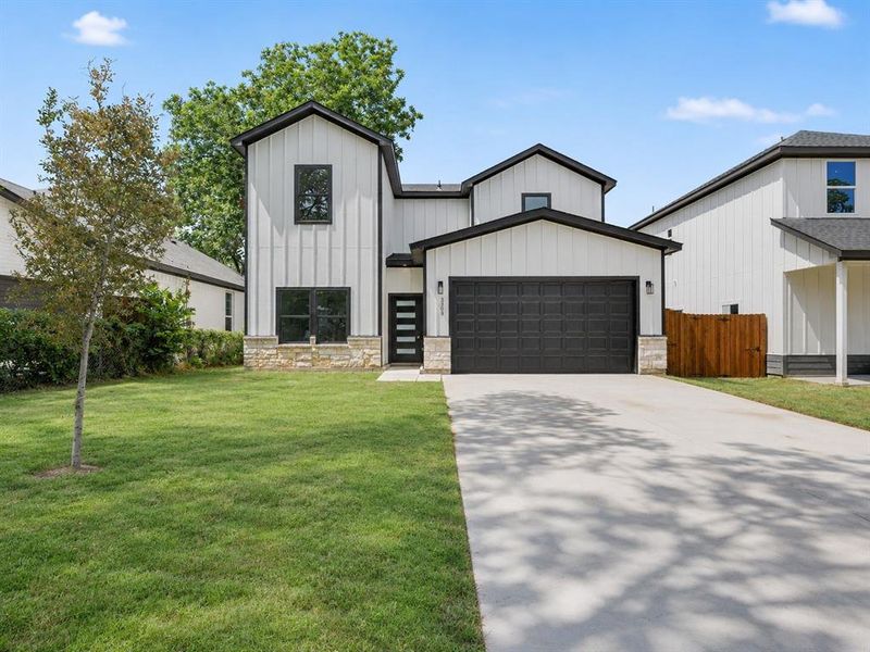 Contemporary two-story residence featuring board and batten siding, a dark panel garage door, stone accents, black window trim, and a concrete driveway Contemporary two-story residence featuring board and batten siding, a dark panel garage door, stone accents, black window trim, and a concrete driveway