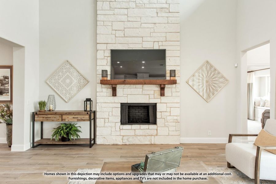 Living room with floor-to-ceiling stone fireplace, wood mantel, wall-mounted TV, and light wood floors