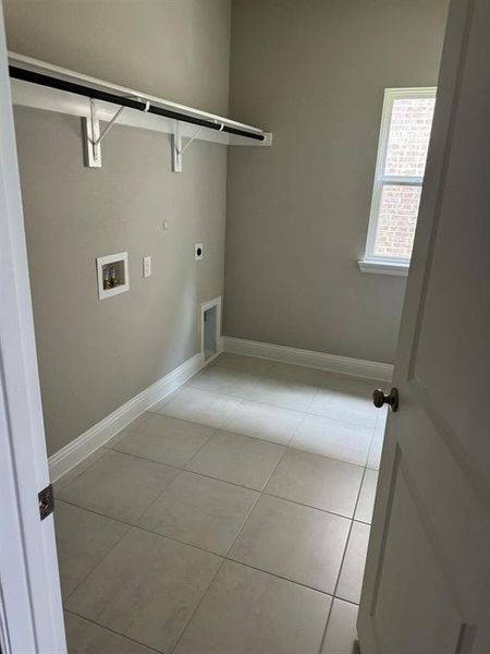 Laundry area featuring washer hookup, electric dryer hookup, and light tile patterned floors