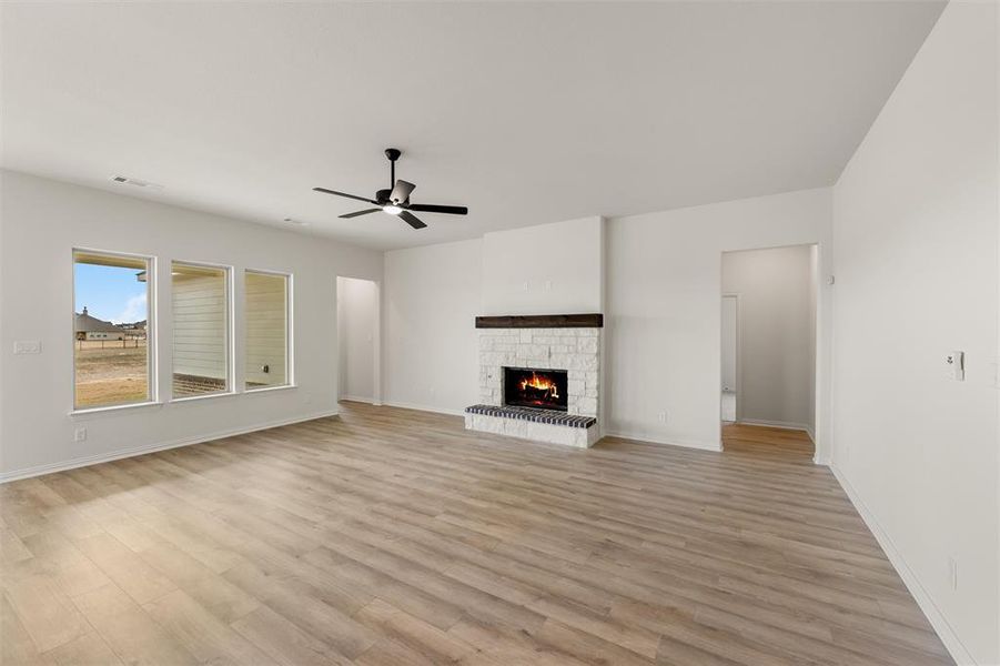 Unfurnished living room with a ceiling fan, light wood finished floors, and a fireplace