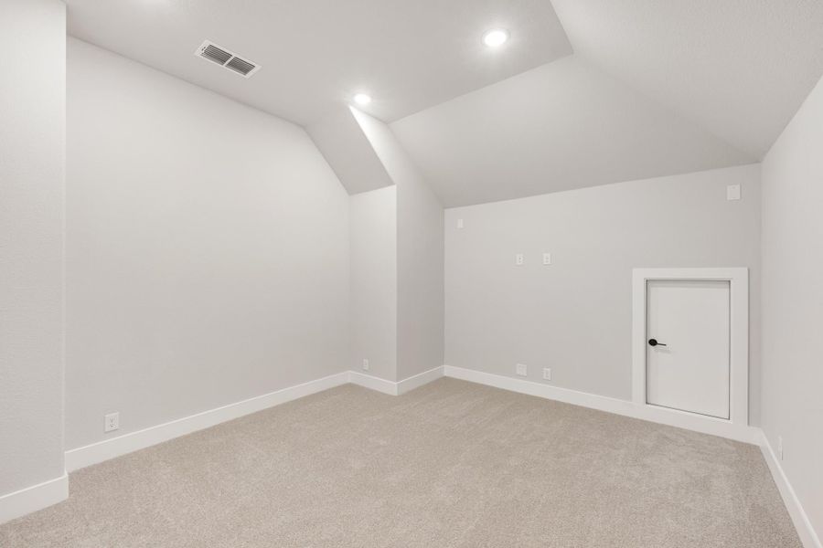 Empty bonus room with angled ceiling, beige carpet, recessed lighting, and a small interior door. Empty bonus room with angled ceiling, beige carpet, recessed lighting, and a small interior door.
