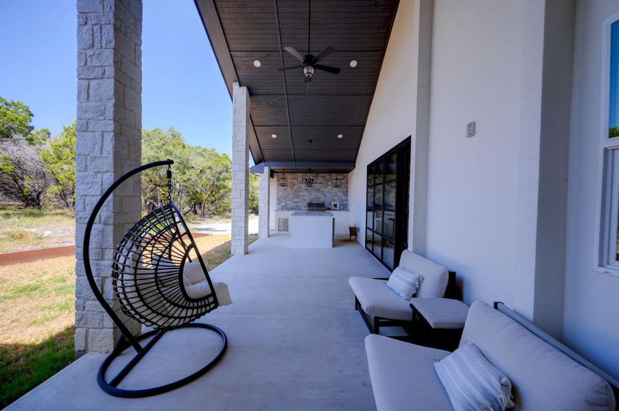 An expansive covered patio features concrete flooring and a rustic stone column.