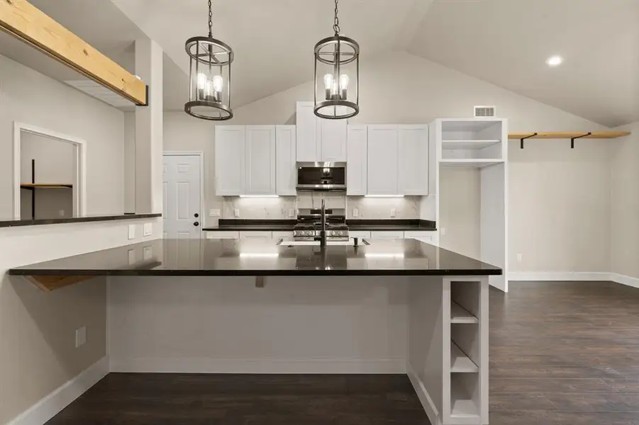 Kitchen with stainless steel appliances, open shelves, dark countertops, tasteful backsplash, and a sink