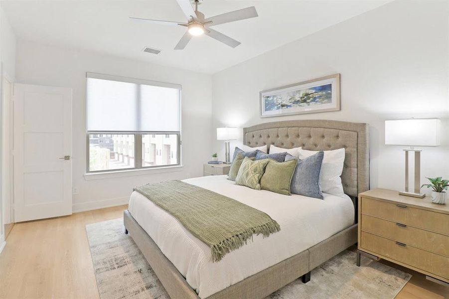 Bedroom with light wood-style floors, visible vents, ceiling fan, and baseboards