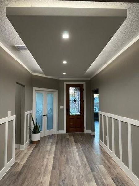 Entryway featuring crown molding, french doors, wood-type flooring, and a textured ceiling