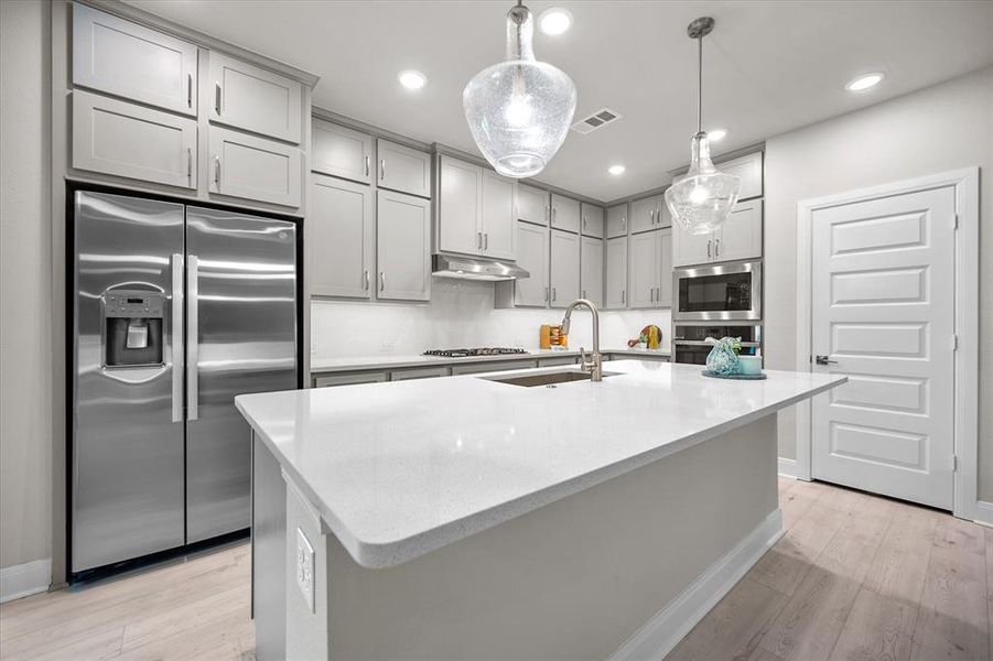 Kitchen featuring appliances with stainless steel finishes, gray cabinetry, light wood-style flooring, recessed lighting, and pendant lighting Kitchen featuring appliances with stainless steel finishes, gray cabinetry, light wood-style flooring, recessed lighting, and pendant lighting