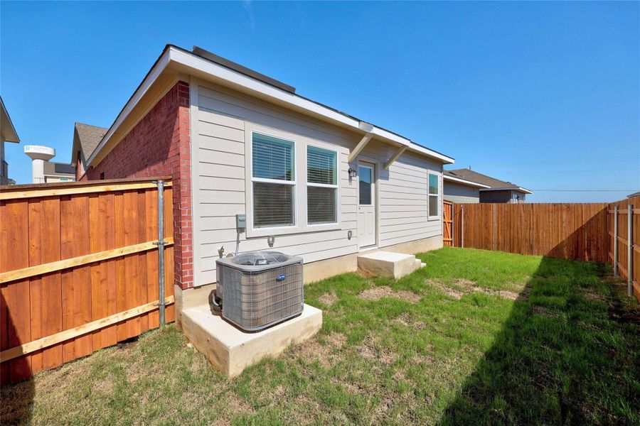 Back of property with a fenced backyard and brick siding