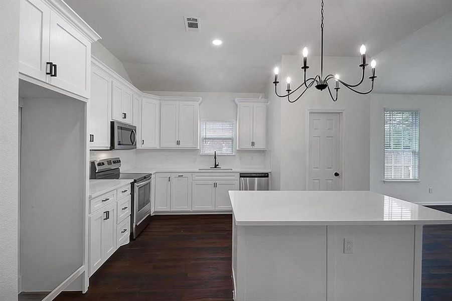 Kitchen with appliances with stainless steel finishes, white cabinets, and dark hardwood / wood-style flooring