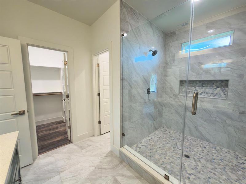 Spacious walk-in shower featuring a glass enclosure, gray-veined tile walls, and a mosaic tile shower floor