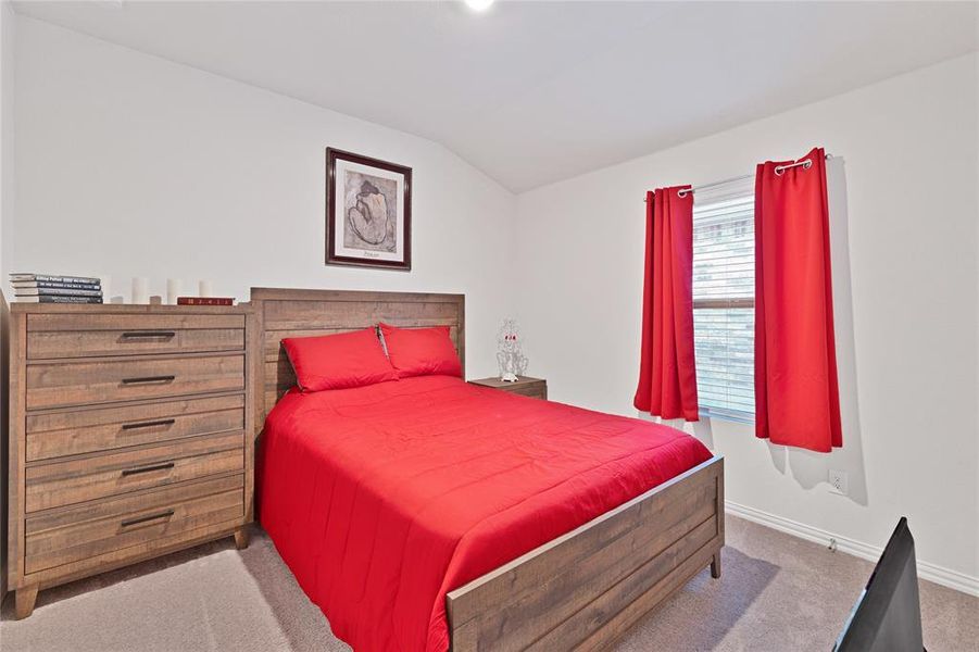 Carpeted bedroom with baseboards and vaulted ceiling