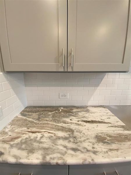 Close up of Fantasy Brown granite counters, white subway tile backsplash, & Grey Shaker cabinets with hardware & soft closing features