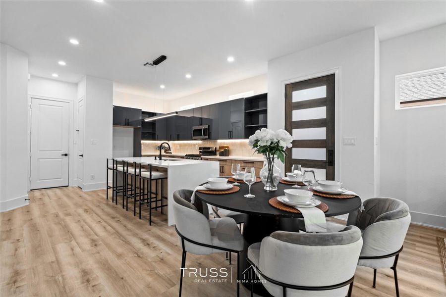 Recessed and designer pendant lighting illuminate the open-concept living space, accentuating the clean architectural lines, warm wood tones, and sophisticated modern finishes throughout the home.