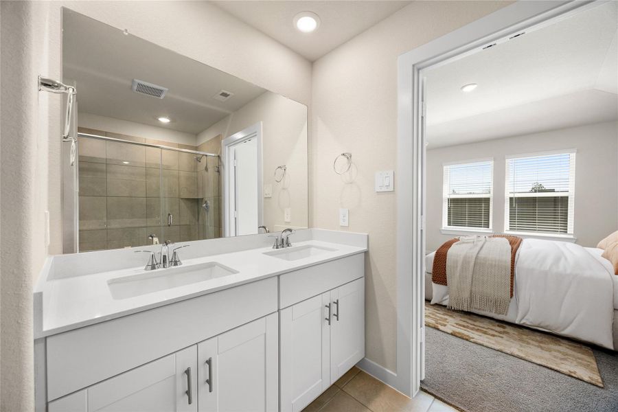 Retreat to a luxurious primary bath designed for relaxation and refinement. A frameless glass shower, dual quartz vanities, and elegant tile details create a spa-like ambiance, perfectly complementing the sophistication of the adjoining primary suite.