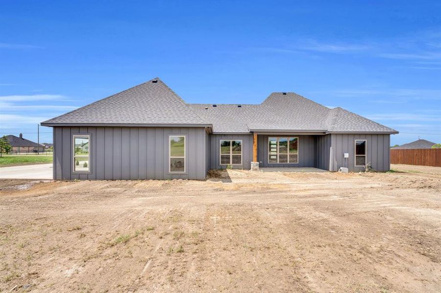 Rear view of house featuring roof with shingles and a patio