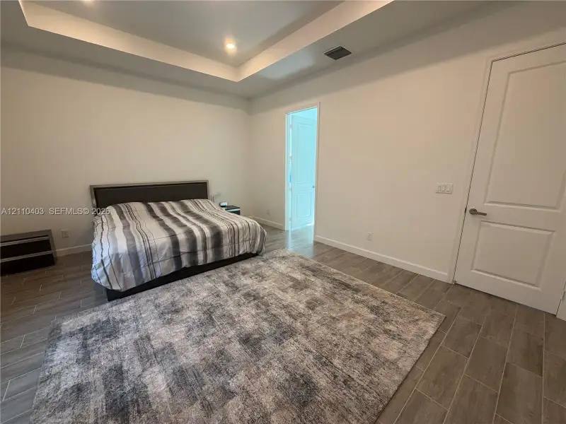 Tray ceiling with recessed lighting and wood-finish tile flooring
