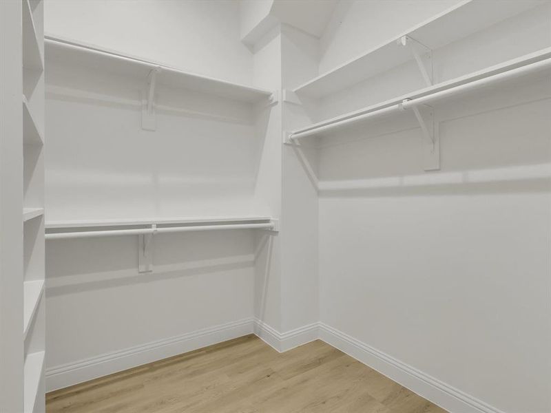 Walk in closet with hardwood / wood-style floors