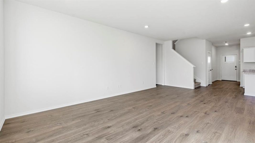 Unfurnished living room featuring dark wood-type flooring, stairs, and recessed lighting
