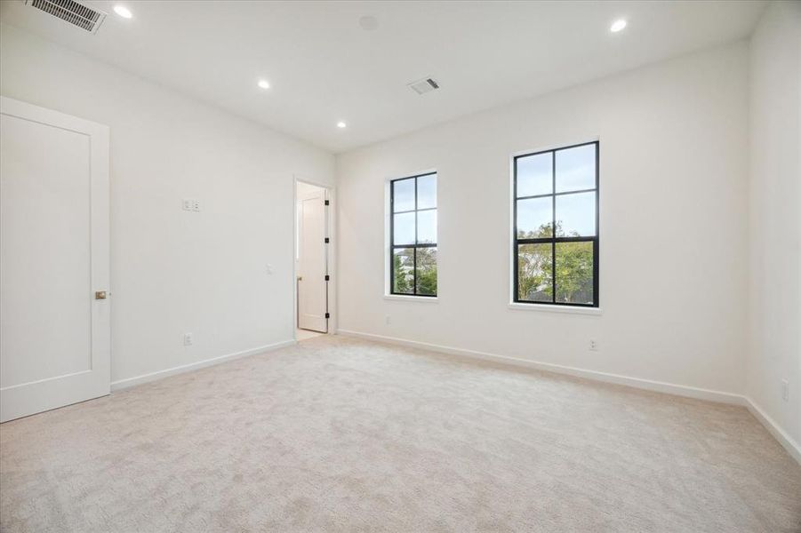 Bright and airy bedroom featuring plush carpet, high ceilings, and large windows that invite plenty of natural light. The room offers a clean, modern aesthetic and a neutral palette for easy customization. Hollywood bath with private vanity and shared shower/tub combo.