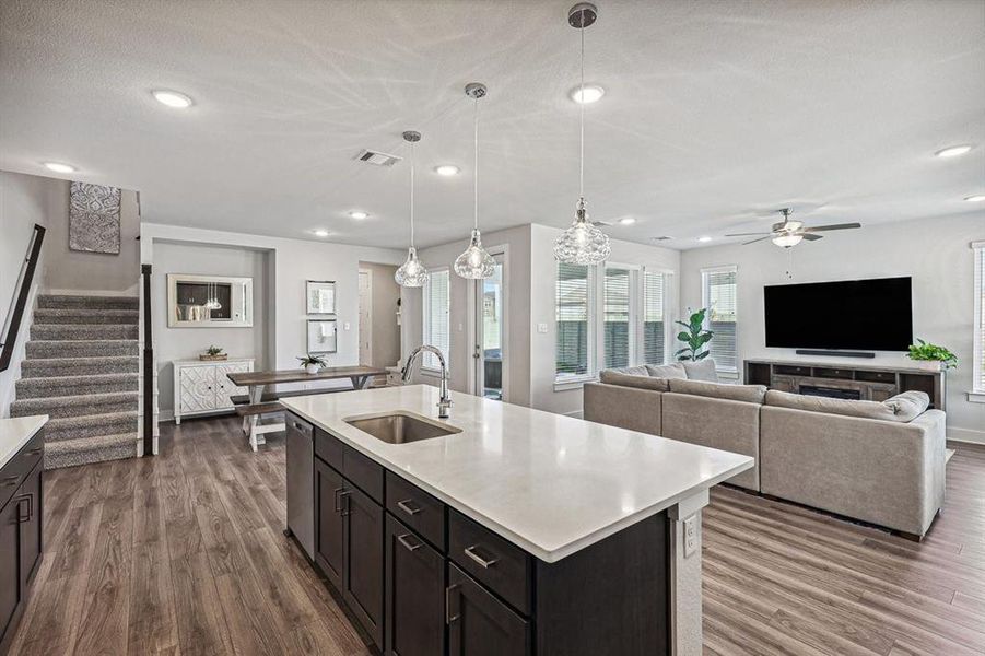 Kitchen with a kitchen island with single basin sink, decorative pendant lights, and picture windows