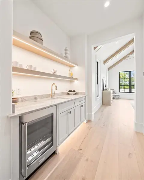 Bar area featuring wine cooler, open shelves, light stone countertops, light wood-type flooring, and recessed lighting