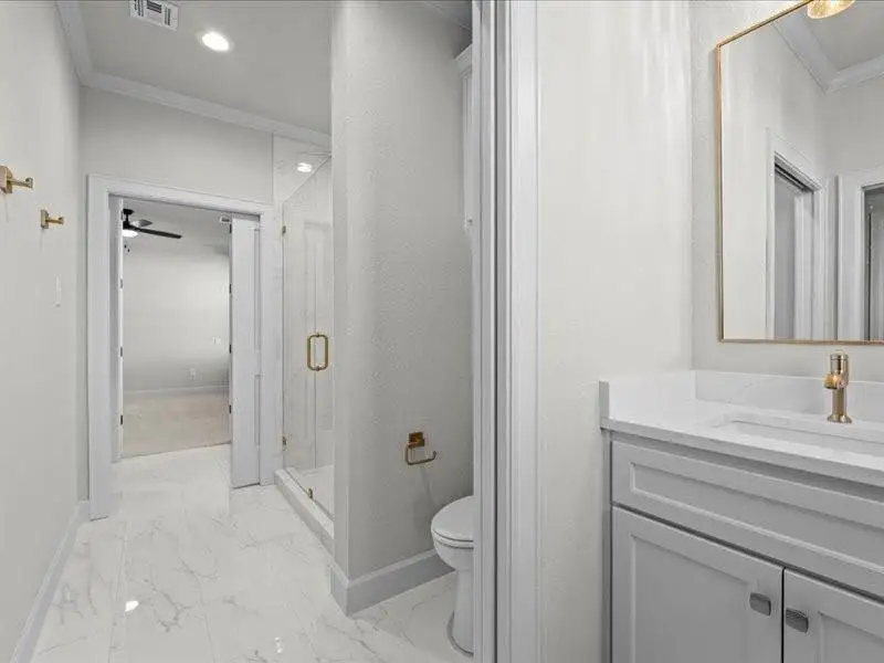 Bathroom with crown molding, a marble finish shower, vanity, light marble finish floors, and a ceiling fan Bathroom with crown molding, a marble finish shower, vanity, light marble finish floors, and a ceiling fan