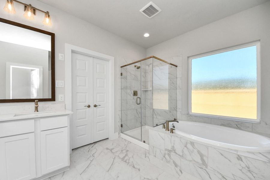 Indulge in a spa-like retreat within the confines of this primary bathroom. Delight in a spacious walk-in shower enveloped in stylish tile surround and unwind in a separate garden tub adorned with custom detailing. Indulge in a spa-like retreat within the confines of this primary bathroom. Delight in a spacious walk-in shower enveloped in stylish tile surround and unwind in a separate garden tub adorned with custom detailing.