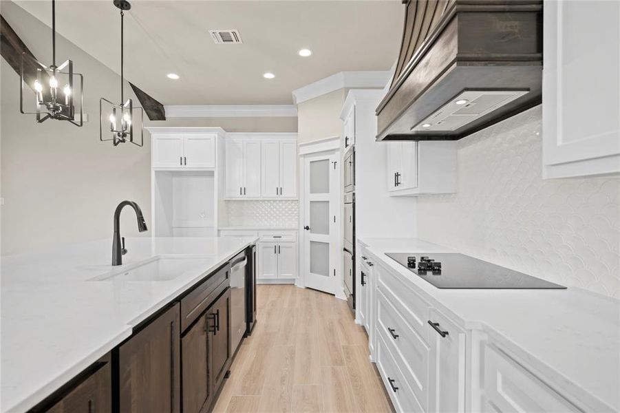 Kitchen featuring white cabinetry, decorative backsplash, light stone countertops, hanging light fixtures, and ornamental molding