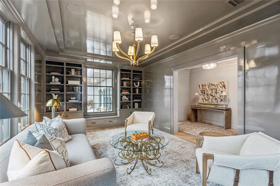 Sitting room featuring baseboards, an inviting chandelier, built in features, and crown molding