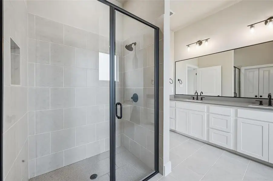 Full bathroom with double vanity, a stall shower, and light tile patterned flooring