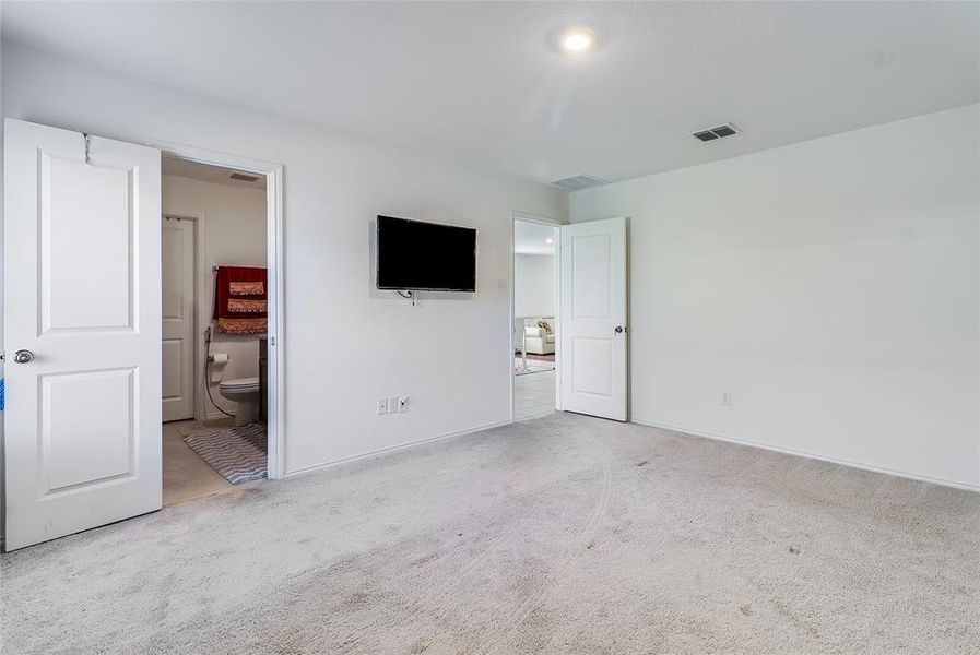 Unfurnished bedroom featuring light colored carpet and connected bathroom