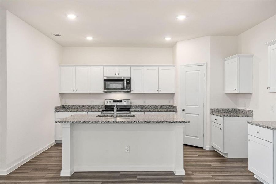 Kitchen featuring white cabinetry, light stone countertops, stainless steel appliances, dark wood finished floors, and recessed lighting Kitchen featuring white cabinetry, light stone countertops, stainless steel appliances, dark wood finished floors, and recessed lighting