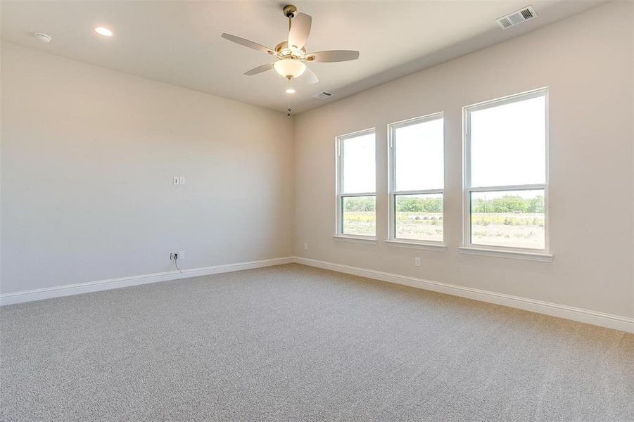 Unfurnished room with carpet floors, plenty of natural light, and ceiling fan