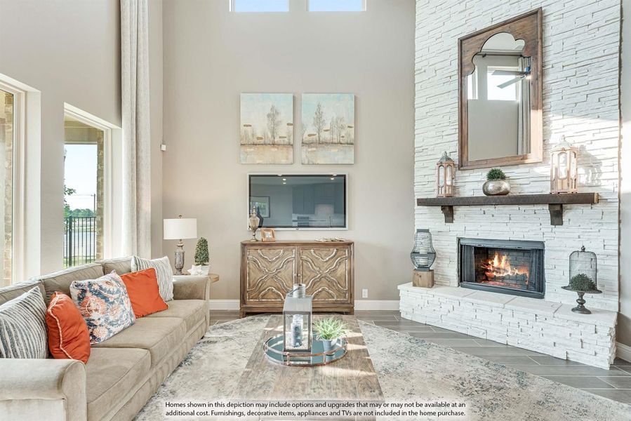 Living room with two-story ceiling, white stacked stone fireplace, beige sofa, and wood media console