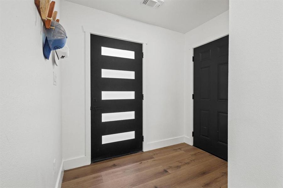 Foyer with dark wood-style floors and baseboards