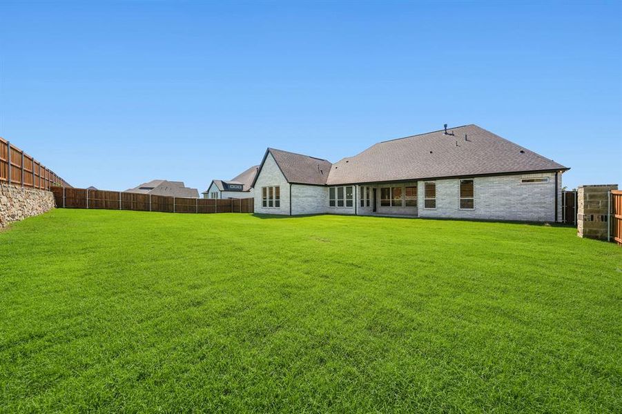 Rear view of house featuring a fenced backyard, a patio, brick siding, and roof with shingles