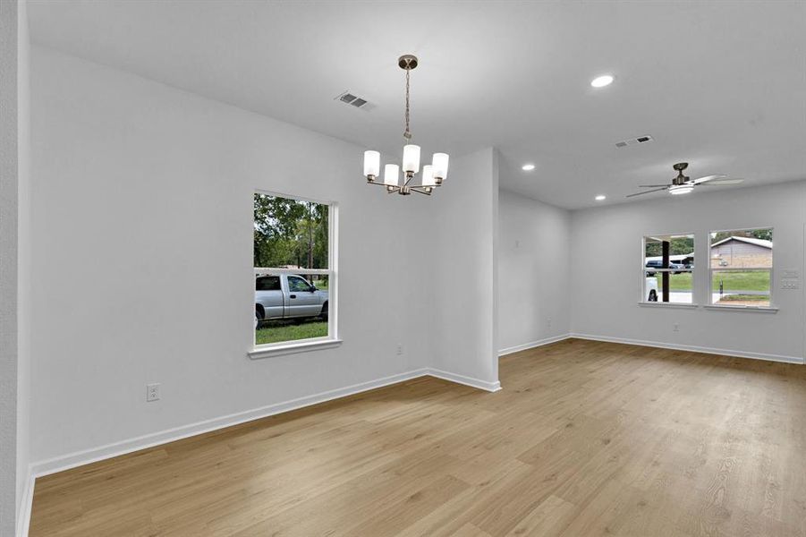 Unfurnished room featuring recessed lighting, ceiling fan, light wood-style flooring, and a chandelier Unfurnished room featuring recessed lighting, ceiling fan, light wood-style flooring, and a chandelier