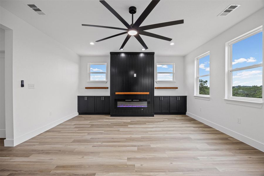 Spacious room featuring wood-finish flooring, a contemporary ceiling fan, and recessed lighting Spacious room featuring wood-finish flooring, a contemporary ceiling fan, and recessed lighting