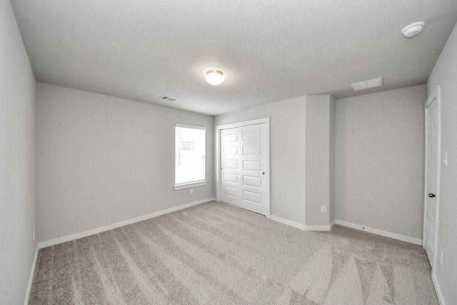 Secondary bedroom features plush carpeting, large windows that let in plenty of natural light, bright paint, and spacious closets. Sample photo of completed home with similar floor plan. Actual colors and selections may vary. Secondary bedroom features plush carpeting, large windows that let in plenty of natural light, bright paint, and spacious closets. Sample photo of completed home with similar floor plan. Actual colors and selections may vary.