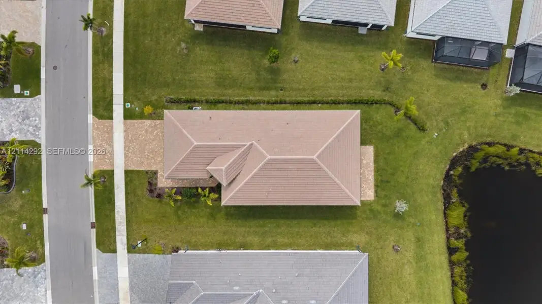 Aerial perspective featuring a tile roof, paved driveway, and water frontage