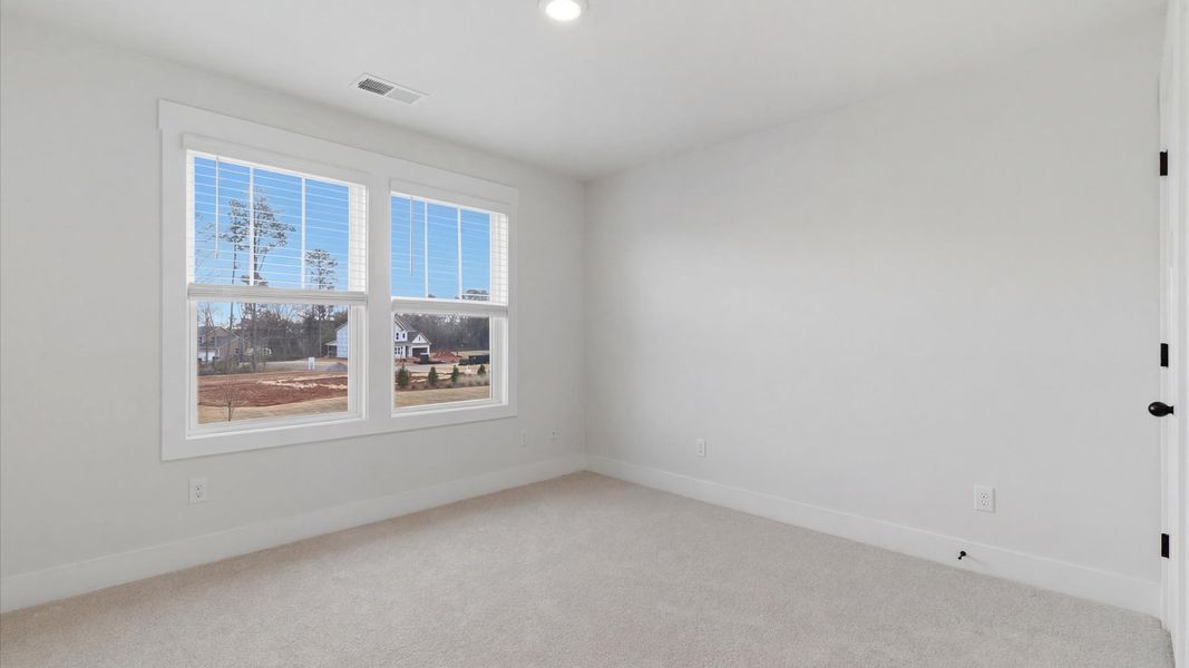 Notable bedroom offering soft carpet, a walk-in closet, and expansive windows overlooking the yard located at Pelham Crossing