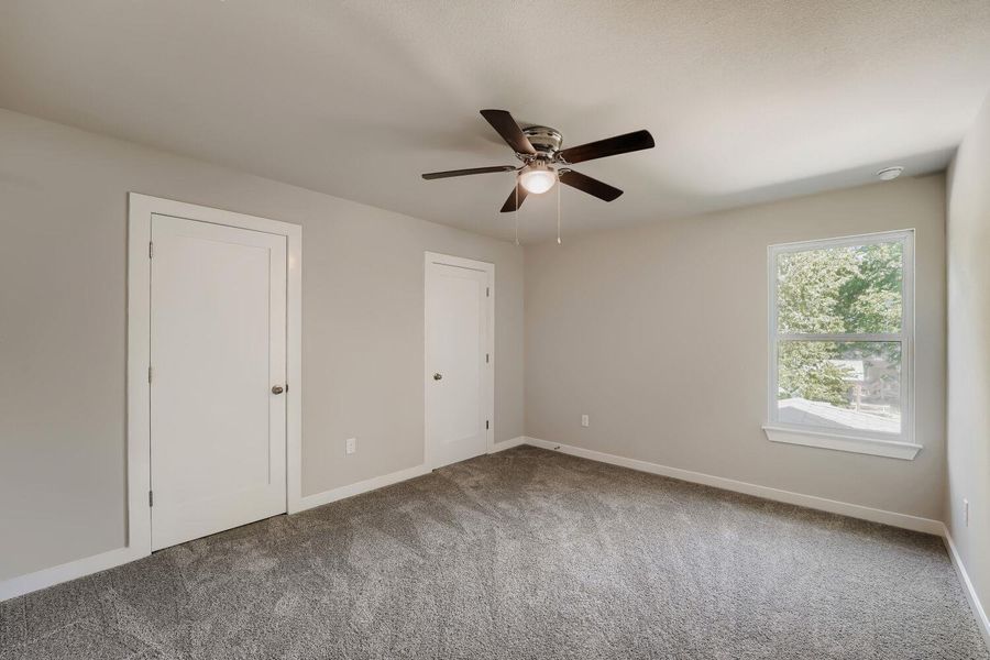 A quiet bedroom featuring plush carpeting and an illuminating ceiling fan, ready for personal touches. A quiet bedroom featuring plush carpeting and an illuminating ceiling fan, ready for personal touches.