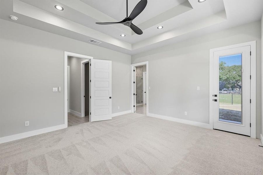 Unfurnished bedroom with a raised ceiling, light colored carpet, recessed lighting, ceiling fan, and access to exterior Unfurnished bedroom with a raised ceiling, light colored carpet, recessed lighting, ceiling fan, and access to exterior