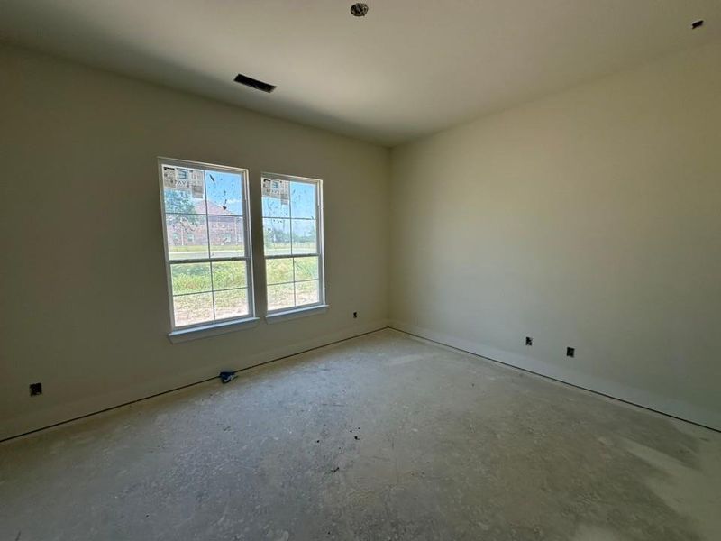 Unfinished interior space featuring two large windows with white trim, light-colored walls, and a concrete floor