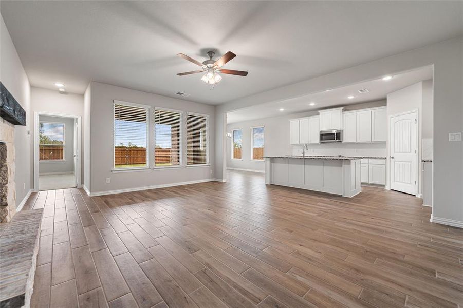 Unfurnished living room with ceiling fan, light wood finished floors, recessed lighting, and a fireplace Unfurnished living room with ceiling fan, light wood finished floors, recessed lighting, and a fireplace