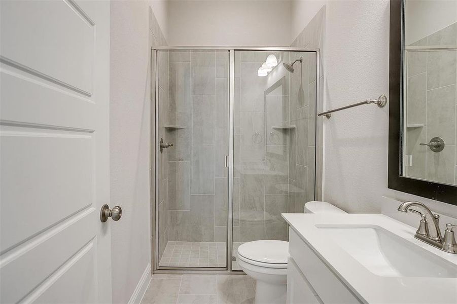 Bathroom featuring vanity, toilet, and a shower with door