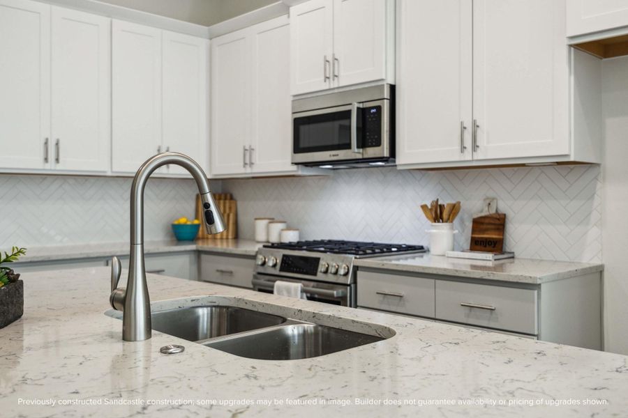From the stainless steel undermount sink to the Moen pull-down faucet, every detail here feels elevated. Designer-selected backsplashes add just the right touch of texture and personality.