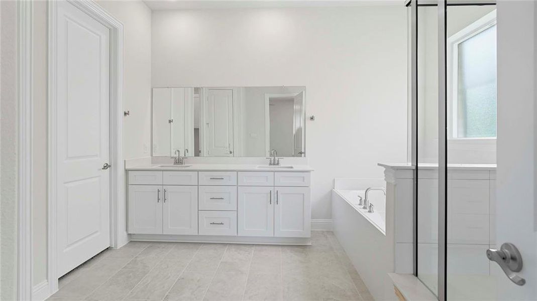 Full bathroom featuring double vanity, a garden tub, and a stall shower