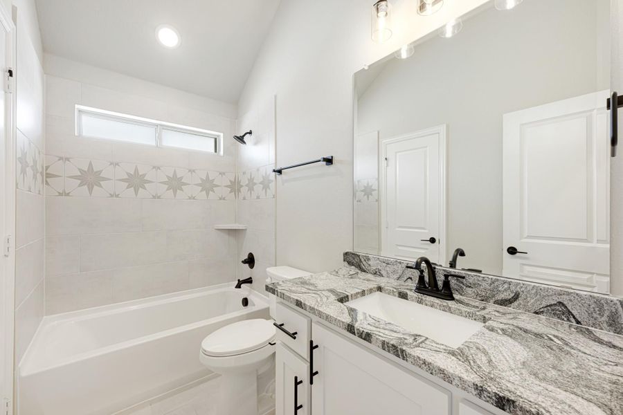 Bathroom with granite countertop vanity, white tub-shower with star tile border, and vaulted ceiling Bathroom with granite countertop vanity, white tub-shower with star tile border, and vaulted ceiling