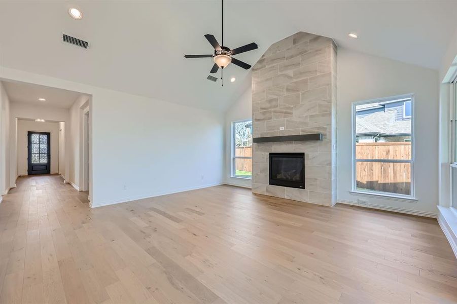 Unfurnished living room featuring high vaulted ceiling, light wood-type flooring, and a wealth of natural light